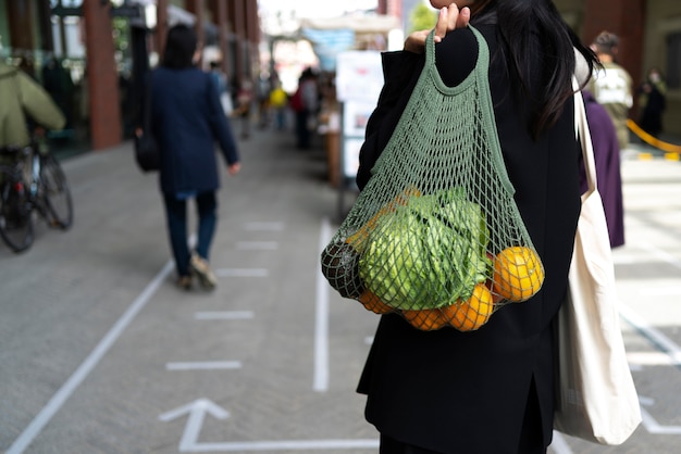 Vista posterior mujer bolsa de transporte con frutas