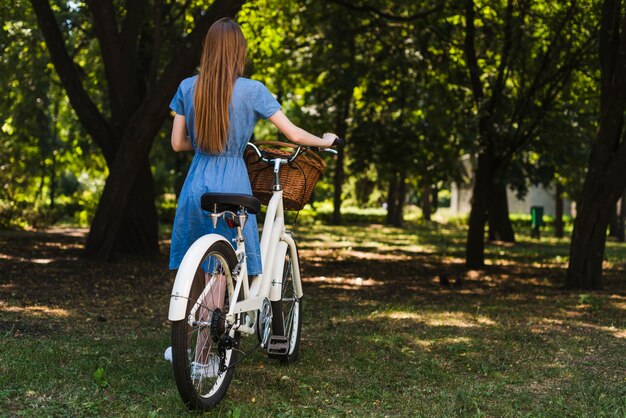 Vista posterior de una mujer caminando al lado de una bicicleta.