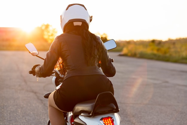 Vista posterior de la mujer con casco en su motocicleta