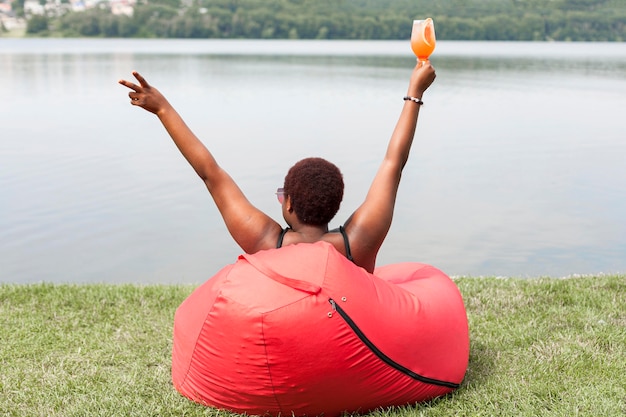 Foto gratuita vista posterior de la mujer disfrutando de un cóctel al aire libre en la bolsa de frijoles