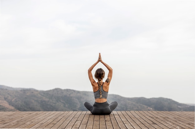 Vista posterior de la mujer haciendo yoga al aire libre