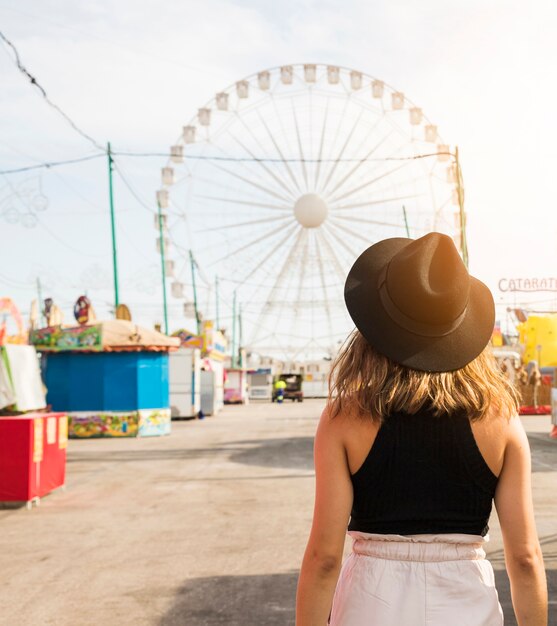 Vista posterior de una mujer joven frente a una pared gigante en el parque de atracciones