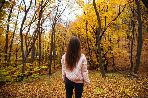 Vista posterior de una mujer joven en el parque de otoño