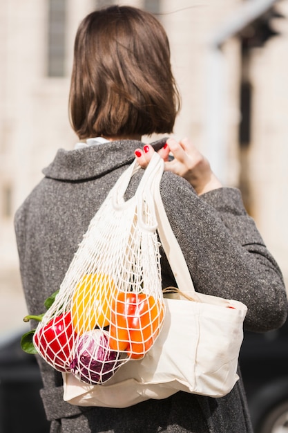 Vista posterior mujer llevando bolsa ecológica con productos orgánicos
