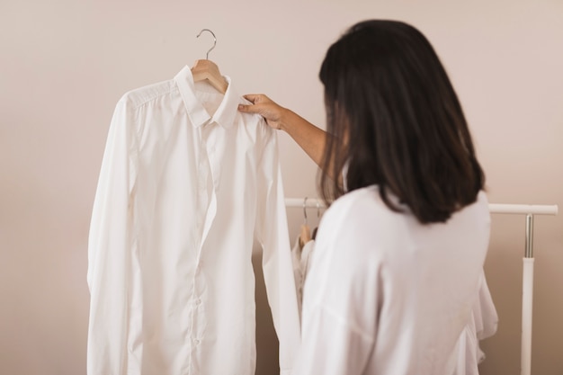 Vista posterior mujer mirando una camisa blanca