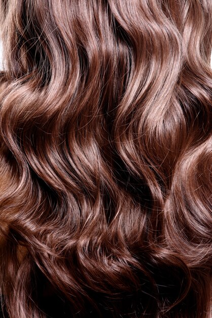 Vista posterior de una mujer morena con el pelo rizado largo y negro posando en el estudio.