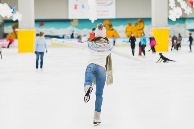 Vista posterior mujer patinando sobre una pierna