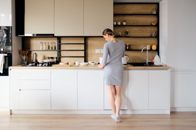 Vista posterior de la mujer de pie junto a una cocina moderna