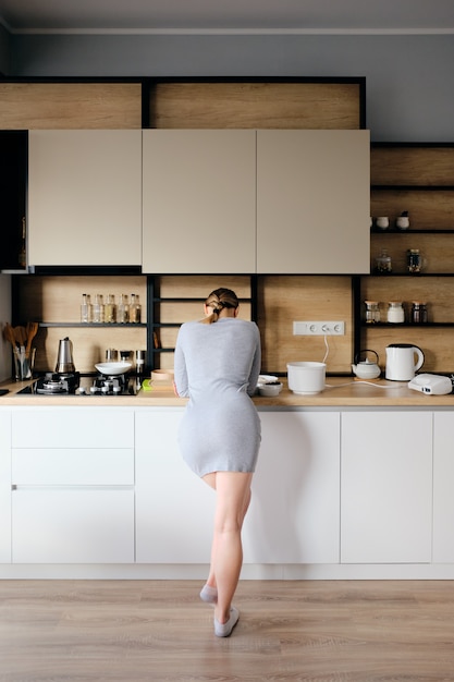 Vista posterior de la mujer de pie junto a una cocina moderna