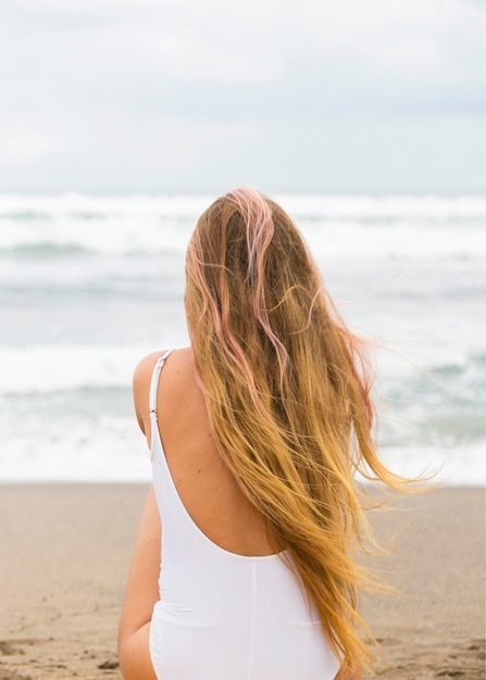 Vista posterior de la mujer en la playa con espacio de copia