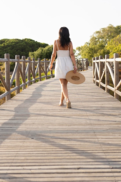 Vista posterior de la mujer posando en el puente en la naturaleza