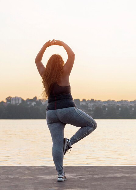 Vista posterior de la mujer practicando yoga al atardecer