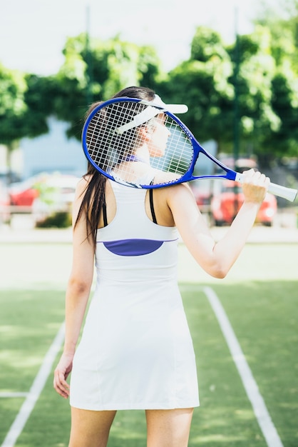 Vista posterior de la mujer en ropa deportiva con raqueta de tenis