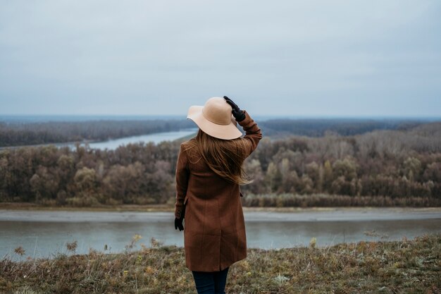 Vista posterior de la mujer con sombrero admirando la vista del lago