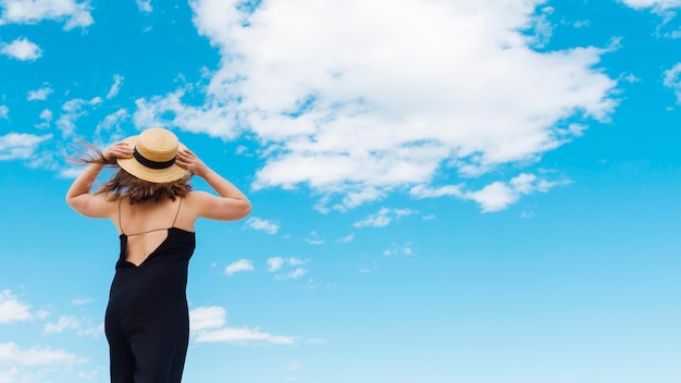 Foto gratuita vista posterior de mujer con sombrero y cielo con nubes
