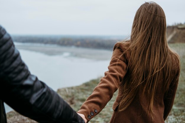 Vista posterior de la mujer sosteniendo la mano de su novio