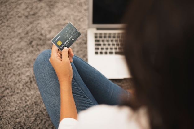 Foto gratuita vista posterior mujer sosteniendo una tarjeta de crédito en el piso