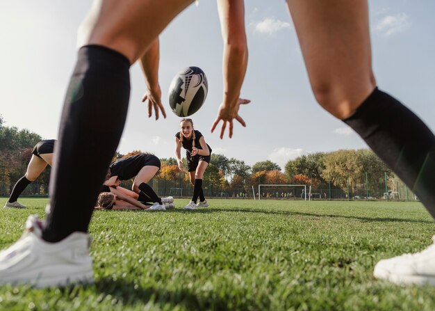 Vista posterior mujeres manos tratando de atrapar una pelota de rugby