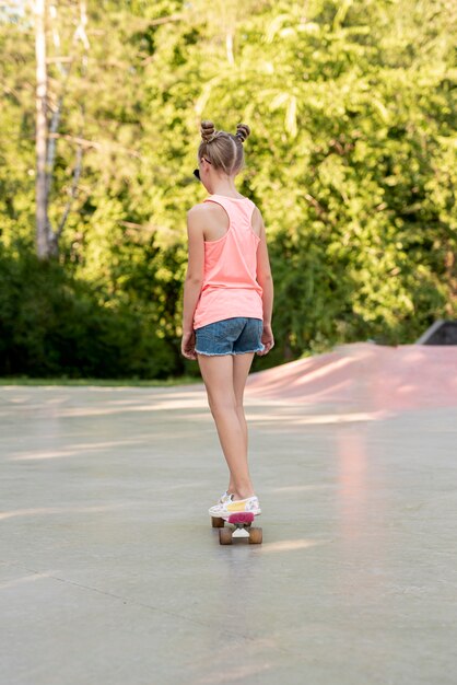 Vista posterior de la niña montando patineta