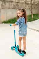 Foto gratuita vista posterior de niña con scooter azul