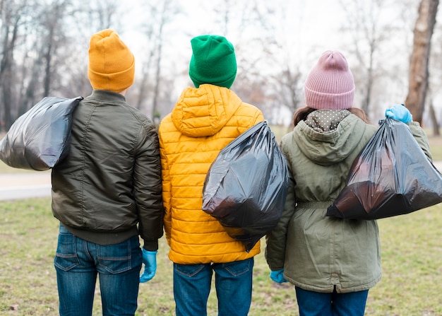 Vista posterior de niños con bolsas de plástico en la espalda