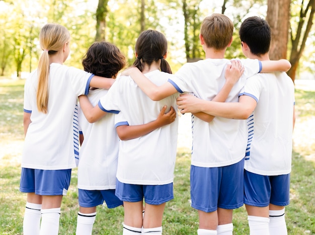 Vista posterior de los niños en ropa deportiva abrazados