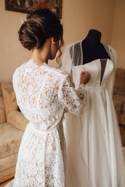 Vista posterior de una novia tierna en la mañana de la boda se está preparando para la ceremonia de la boda