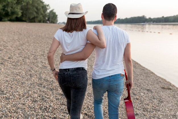 Vista posterior de una pareja abrazándose y caminando por el lago.