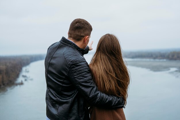 Vista posterior de la pareja admirando la vista al lago