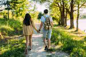 Foto gratuita vista posterior de la pareja cogidos de la mano caminando en el sendero