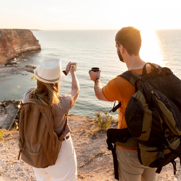 Foto gratuita vista posterior de la pareja disfrutando de una taza de café al atardecer