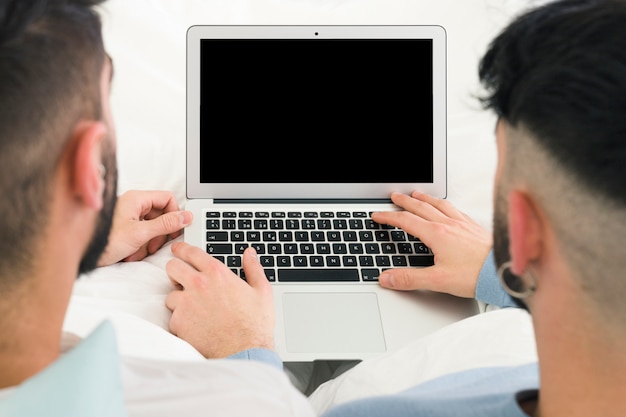 Vista posterior de la pareja gay usando la tableta digital en el escritorio