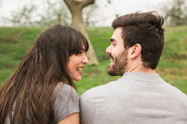 Vista posterior de la pareja joven sonriente mirando el uno al otro