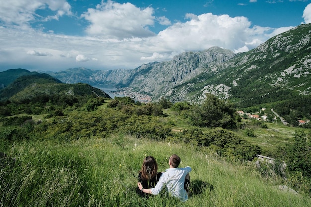 Vista posterior de la pareja romántica disfruta de la vista de las montañas en un día soleado en Montenegro