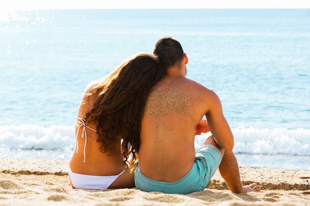 Vista posterior pareja sentada en la playa