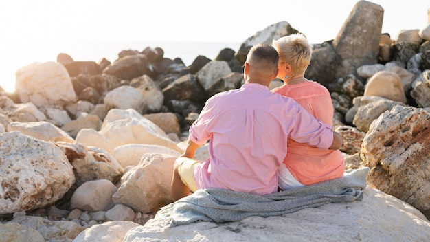 Vista posterior de la pareja sentada en las rocas