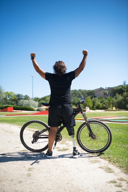 Vista posterior de la persona feliz con discapacidad con bicicleta