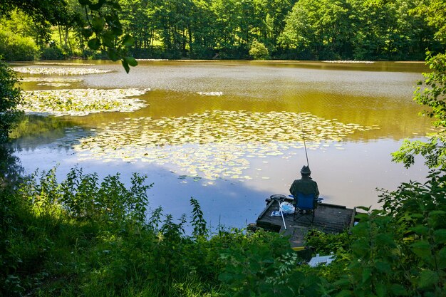 Vista posterior de una persona pesca gruesa en un lago en Wiltshire, Reino Unido, temprano en la mañana