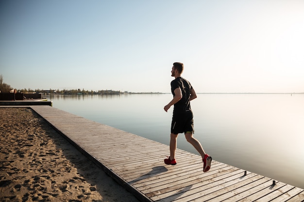 Vista posterior retrato de cuerpo entero de un joven deportista corriendo