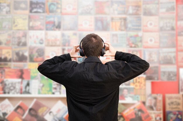 Vista posterior de tiro medio de un hombre joven escuchando música en la tienda