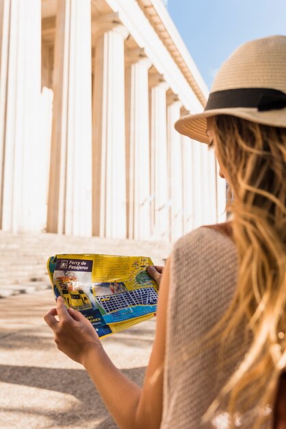 Vista posterior de un turista femenino joven que mira el mapa