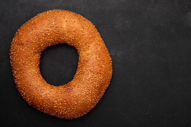 Vista de primer plano de bagel de sésamo turco en el lado izquierdo y fondo negro con espacio de copia