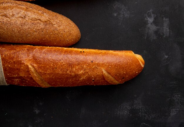 Vista de primer plano de baguettes en el lado izquierdo y fondo negro con espacio de copia