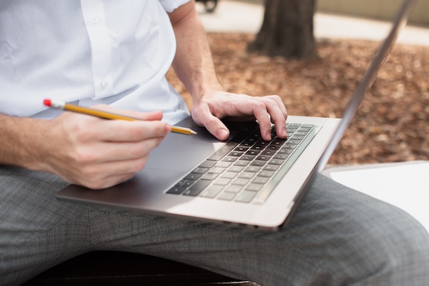 Vista de primer plano del chico sosteniendo su laptop y un lápiz