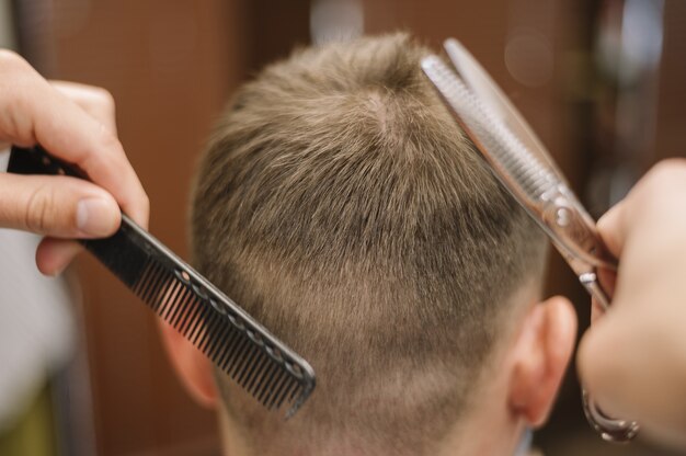 Vista de primer plano de estilista dando un corte de pelo a un cliente