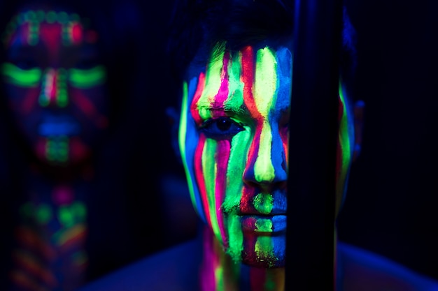 Foto gratuita vista de primer plano del hombre con maquillaje fluorescente y palo