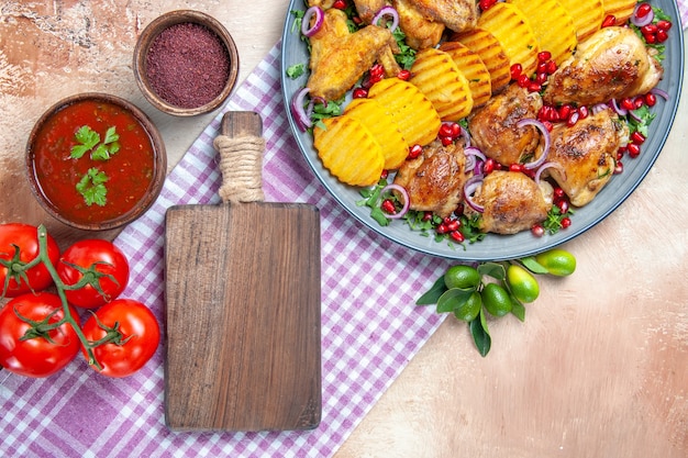 Vista de primer plano superior plato salsa especias tomates pollo con patatas la tabla de cortar