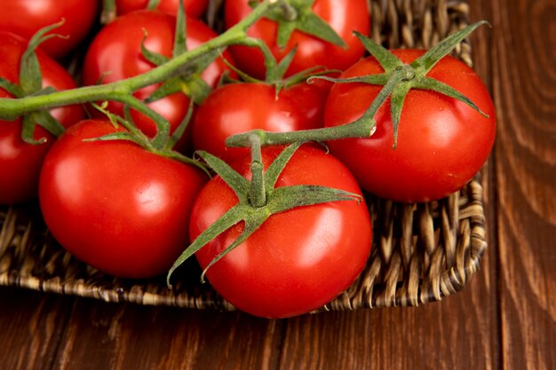 Vista de primer plano de tomates en el plato de la cesta en la mesa de madera