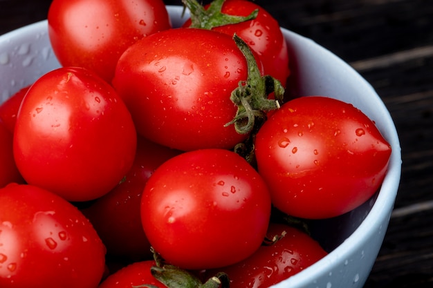 Vista de primer plano de tomates en un recipiente en la mesa de madera