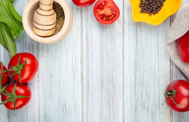 Foto gratuita vista de primer plano de verduras como espinacas de tomate con pimienta negra trituradora de ajo en la mesa de madera con espacio de copia